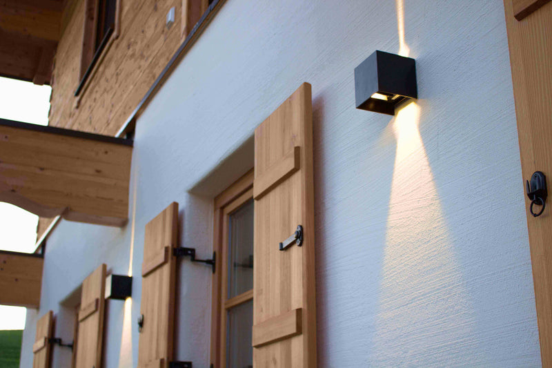 Moderne Außenbeleuchtung an Holzfassade mit Fensterläden, s.luce Lichtakzent auf Wand.