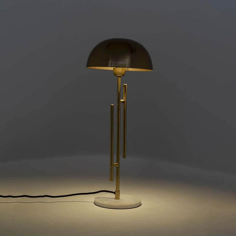 Tischleuchte Solo Brass mit elegantem Design und stilvollem, goldfarbenem Lampenschirm auf einer weißem Basis.