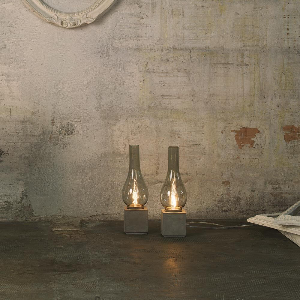 Karman Amarcord Tischlampe in Rauchglas-Optik auf rustikalem Tisch, elegante Lichtquelle für jeden Wohnbereich.