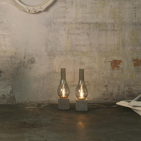 Karman Amarcord Tischlampe in Rauchglas-Optik auf rustikalem Tisch, elegante Lichtquelle für jeden Wohnbereich.