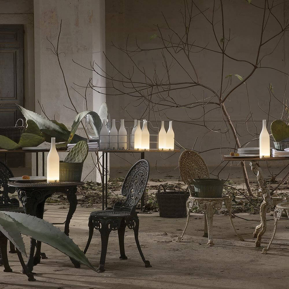 Karman Bacco LED-Tischleuchten in Flaschenform auf einem Tisch im stilvollen Ambiente.