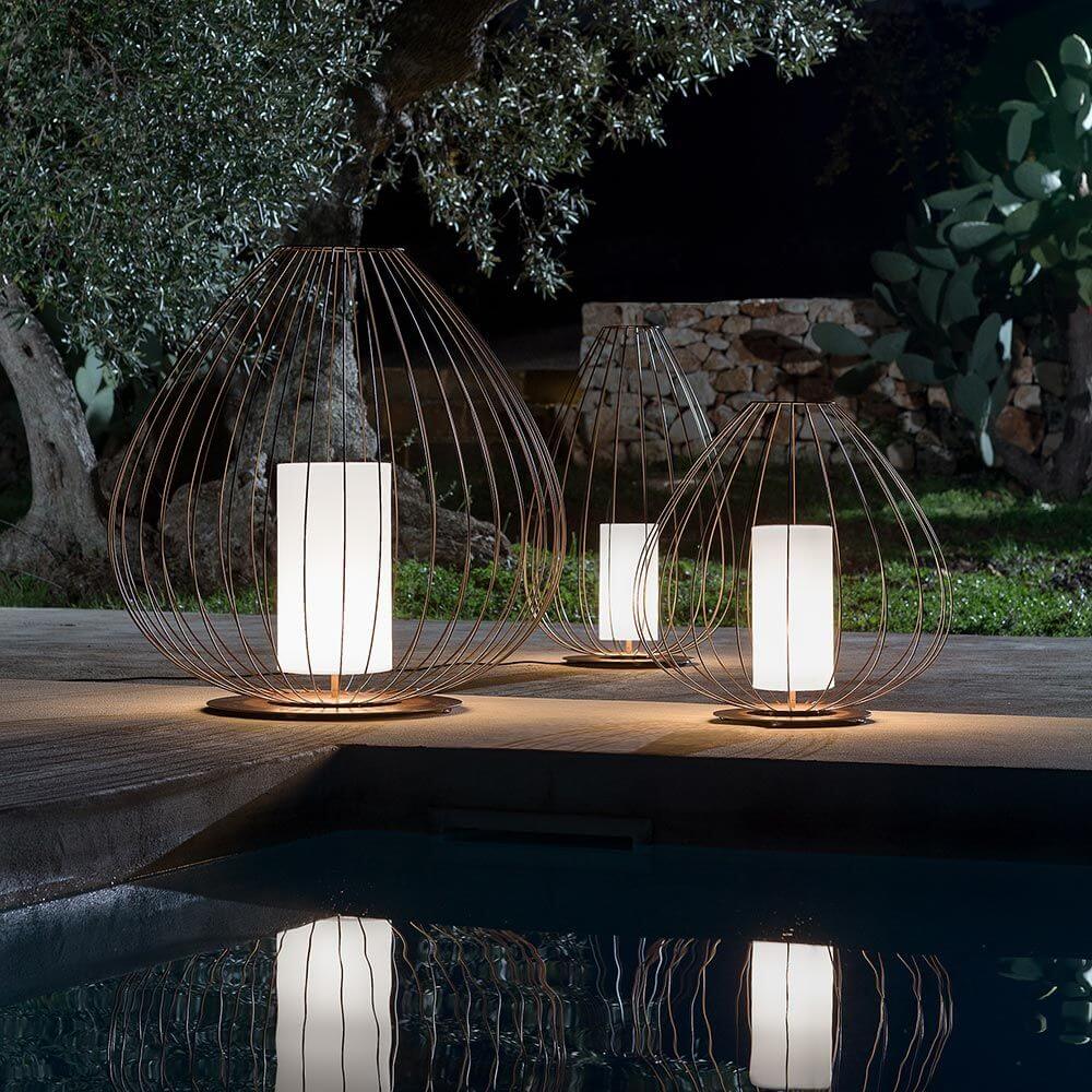 Karman Cell Outdoor-Bodenlampe IP65 mit Drahtgestänge, elegant beleuchtet im Garten nähe Pool.