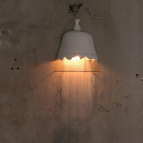 Karman Domenica gips-vegglampe med et fint metallgitter mot en ru, veggbakgrunn.