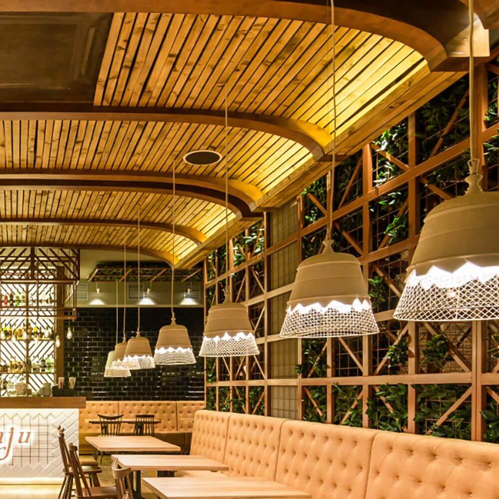 Elegante Karman Domenica Hängeleuchte aus Gips & Metall in einem modernen Restaurant mit Holzdecke.