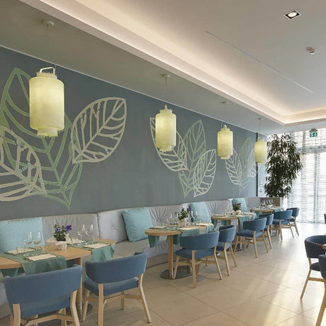 Karman Kimono Hängeleuchte im modernen Restaurant mit minimalistischer Einrichtung und Pflanzenmotiven an der Wand.