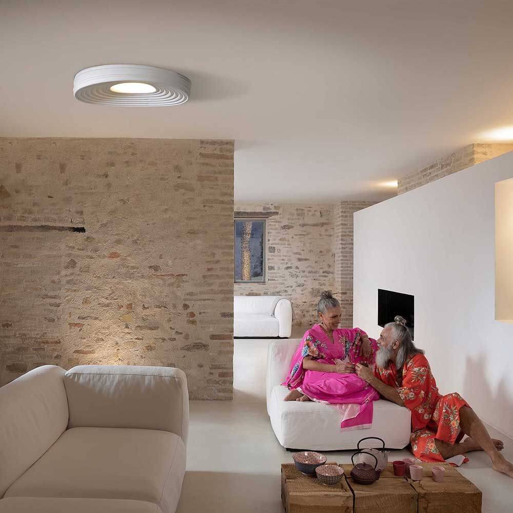 Karman LED-Deckenleuchte R.O.M.A. in modernem Wohnraum über zwei Freunden, die entspannen.