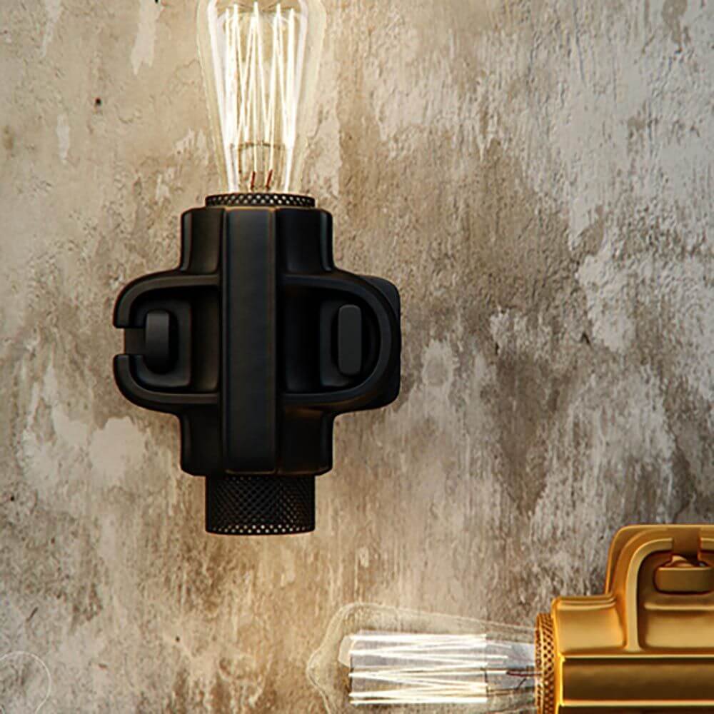 Karman Nando Wandleuchte in Schwarz mit vintage Glühbirne an einer rauen Wand.