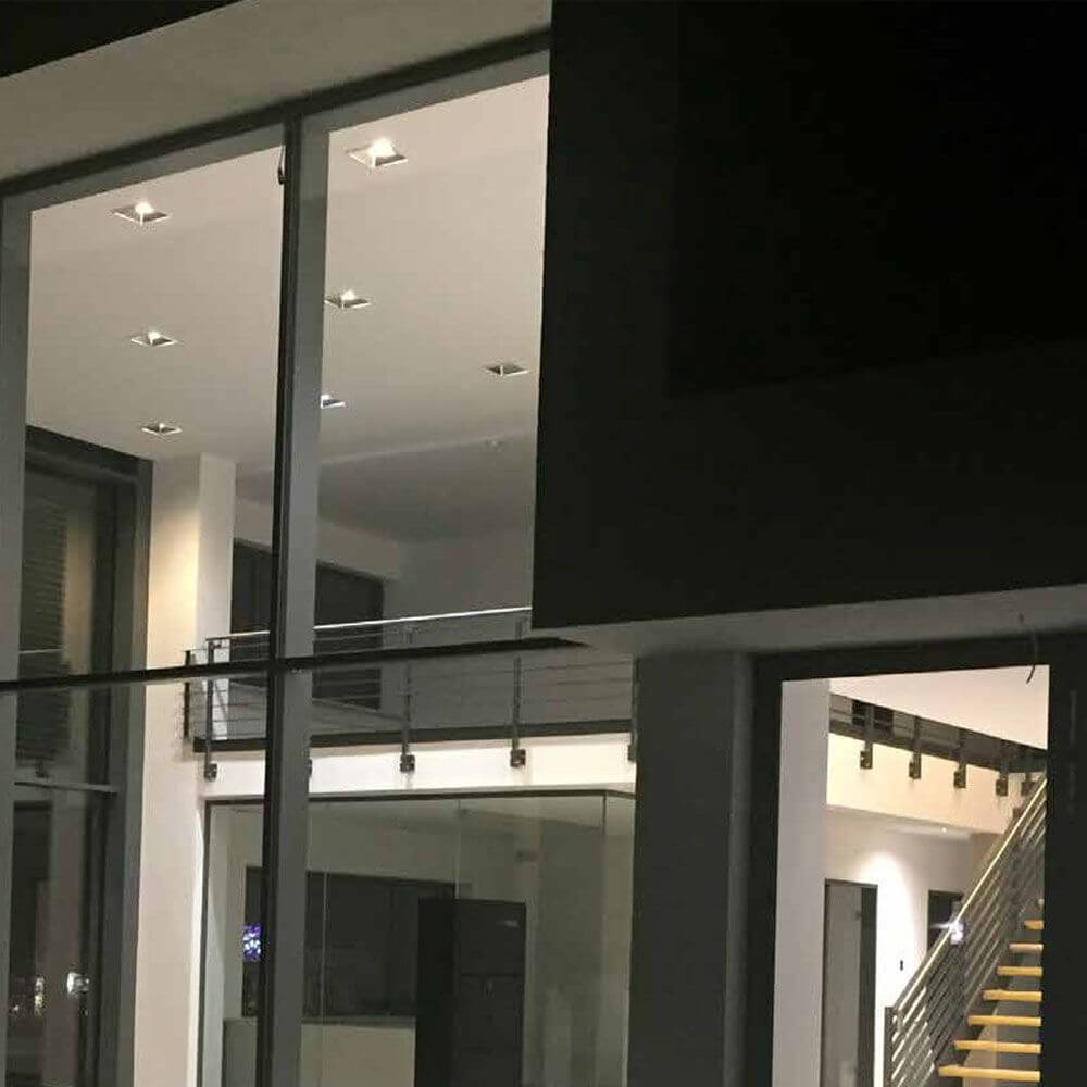 Moderne Innenansicht eines Hauses mit LED-Deckenleuchten und großer Glasfront.