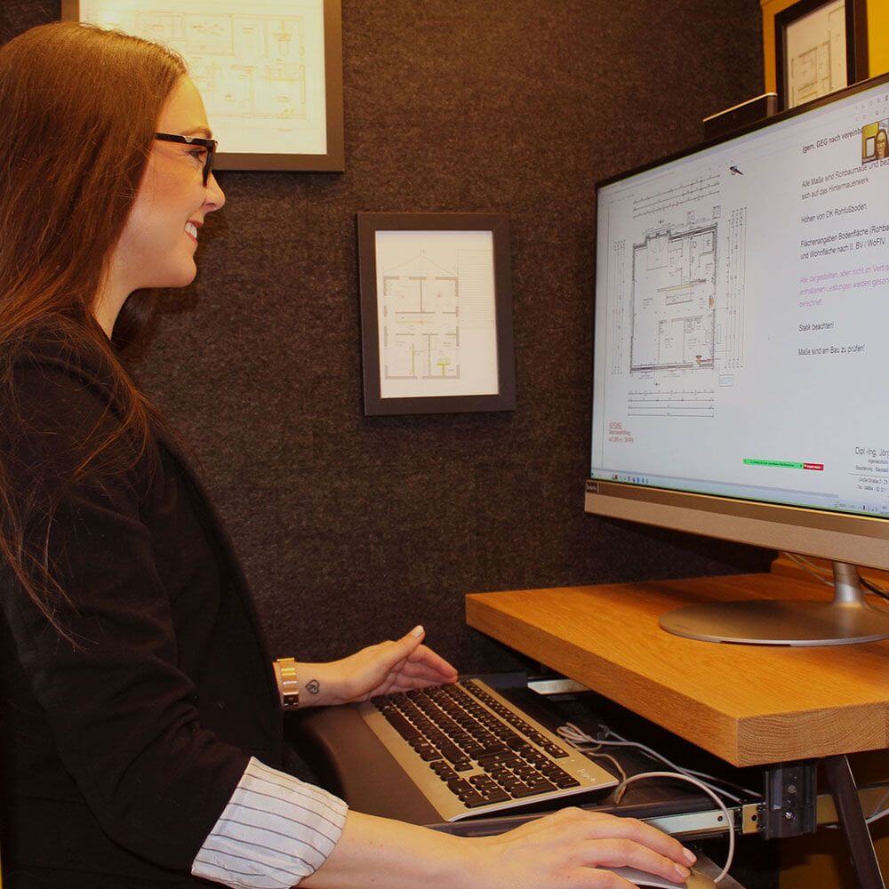 Junge Frau präsentiert kreatives Lichtkonzept am Computer, während sie Pläne prüft und vorbereitet.