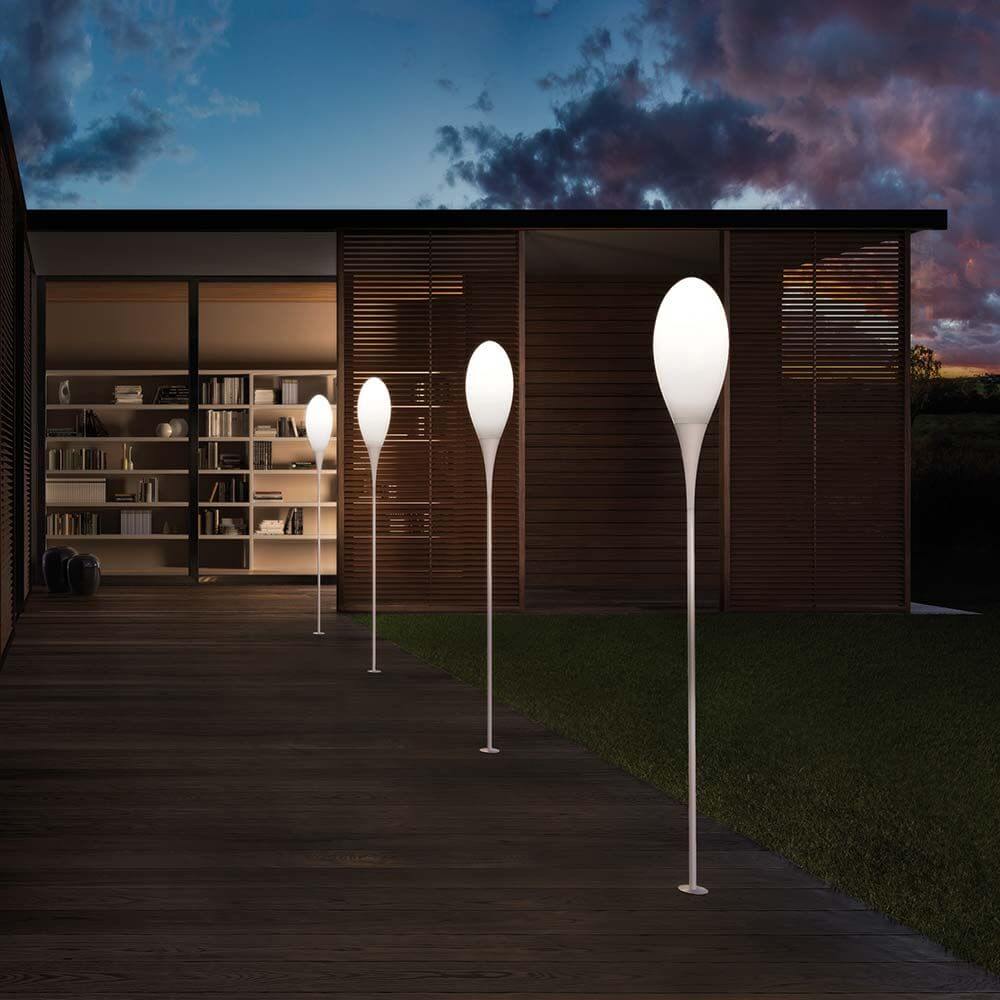 Kundalini Außenbodenleuchte Spillo 150cm in einem modernen Außenbereich mit Holzterrasse bei Abenddämmerung.