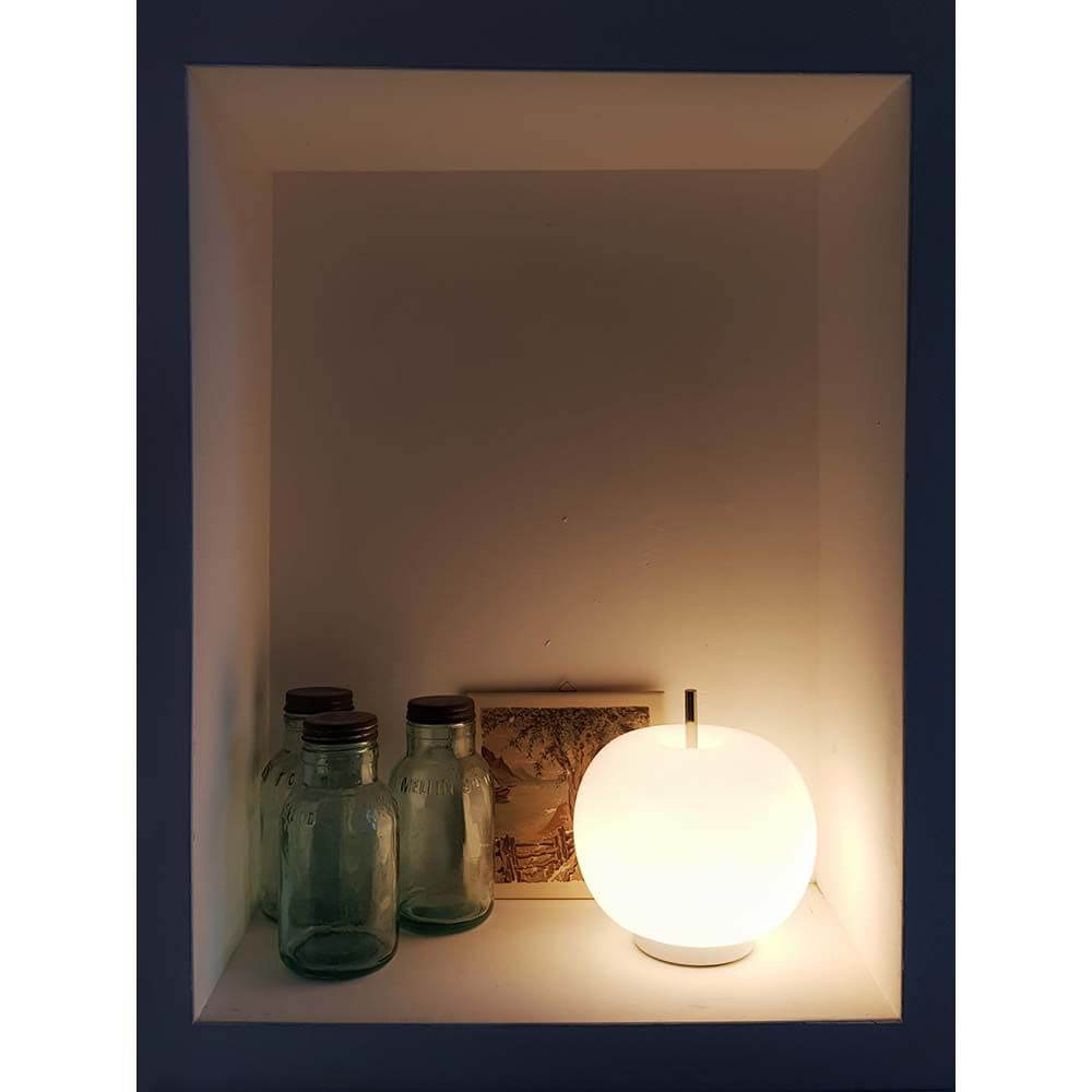 Kundalini Glas Tischlampe Kushi Ø16cm im Regal mit Gläsern und einem Buch.