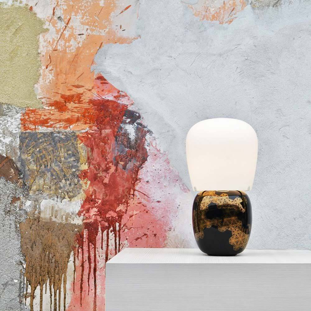 Kundalini Keramik Tischlampe Hive 47cm Dimmbar auf einem modernen Tisch vor einer künstlerischen Wandgestaltung.