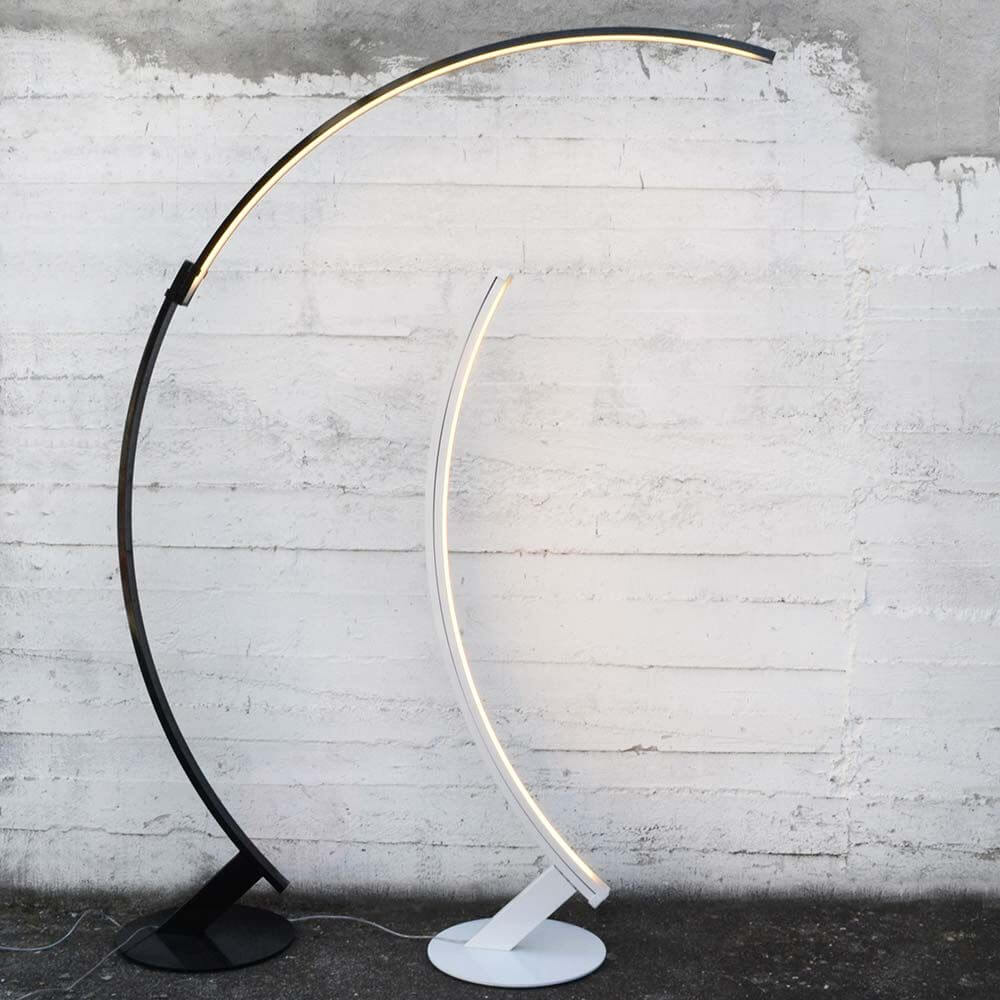 Kundalini LED Bogen-Stehlampe Kyudo Dimmbar in den Farben Schwarz und Weiß vor grauer Wand.