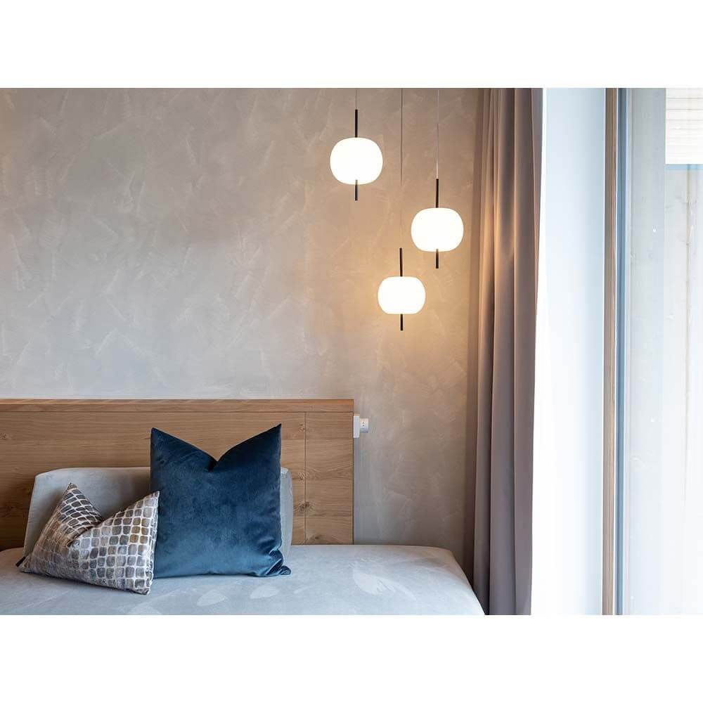 Kundalini Pendellampe Kushi XL Ø 43cm über einem Bett mit eleganten Kissen in gemütlichem Schlafzimmer.