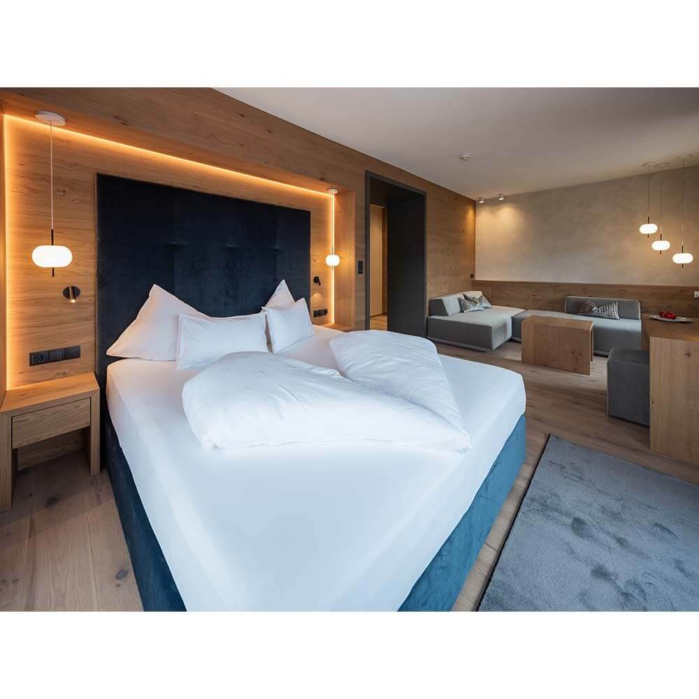 Modernes Schlafzimmer mit bequemen Bett, Holzverkleidung und stilvollen Beleuchtungselementen.