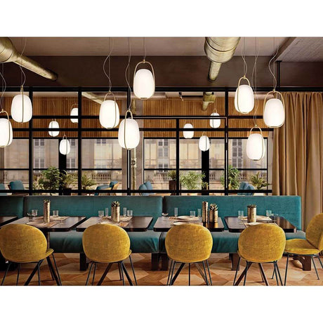 Suspension Kundalini Lanna Ø 22 cm H 40 cm en verre opale dans un restaurant élégant avec des meubles modernes.