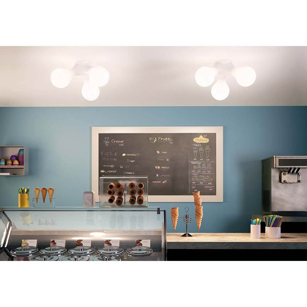 Moderne Kundalini Wandlampe Atomium Weiß in einer stilvollen Eisdiele, die einladendes Licht spendet.