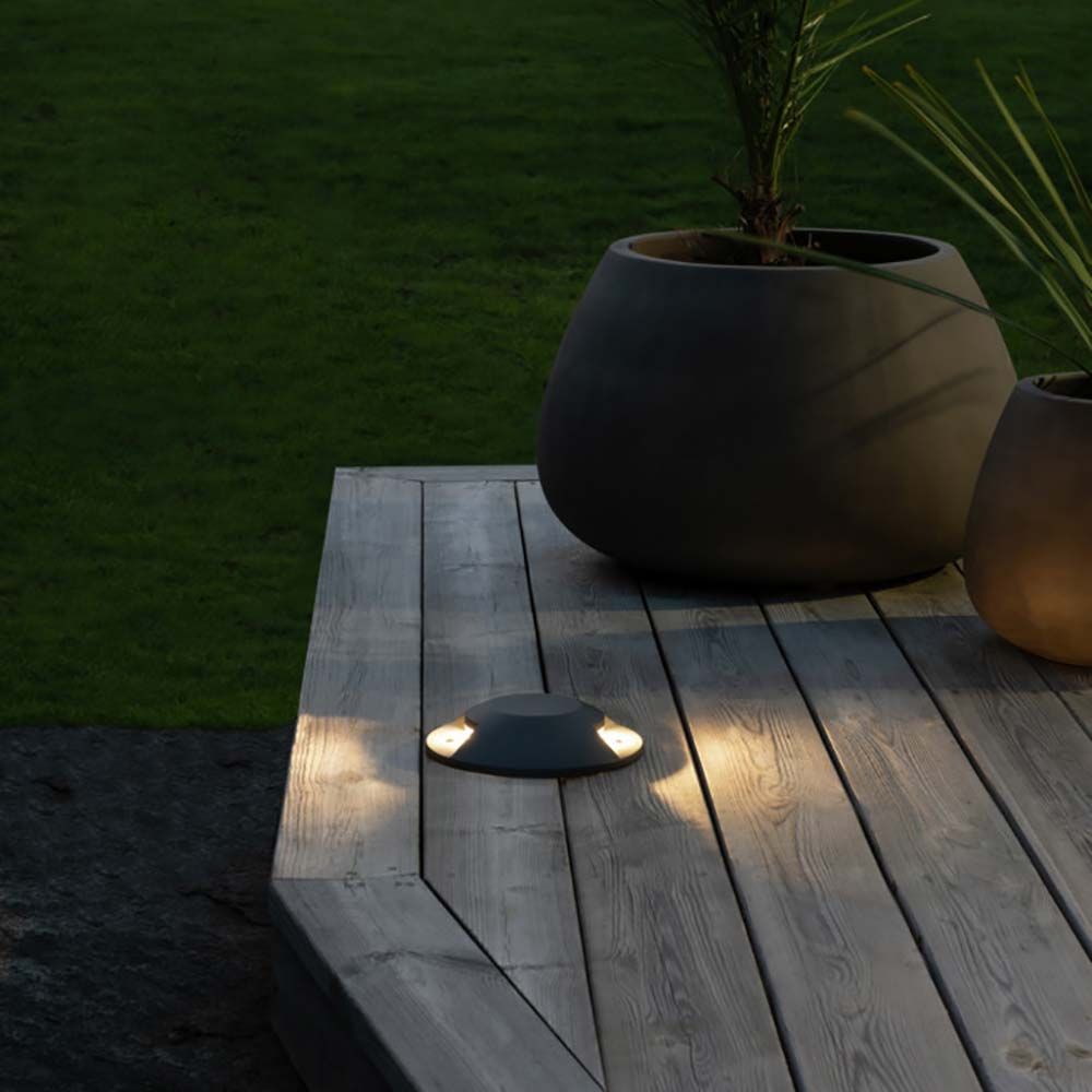 LED 2-Weg Bodeneinbaustrahler auf Holzdielen mit modernen Blumentöpfen im Garten.