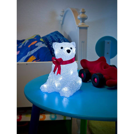 LED Acryl Eisbär mit roter Schleife 16 Kaltweiße Dioden auf einem Tisch im Kinderzimmer.