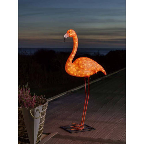 LED Acryl Flamingo groß 96 bernsteinfarbene Dioden IP44 beleuchtet im Garten bei Sonnenuntergang.