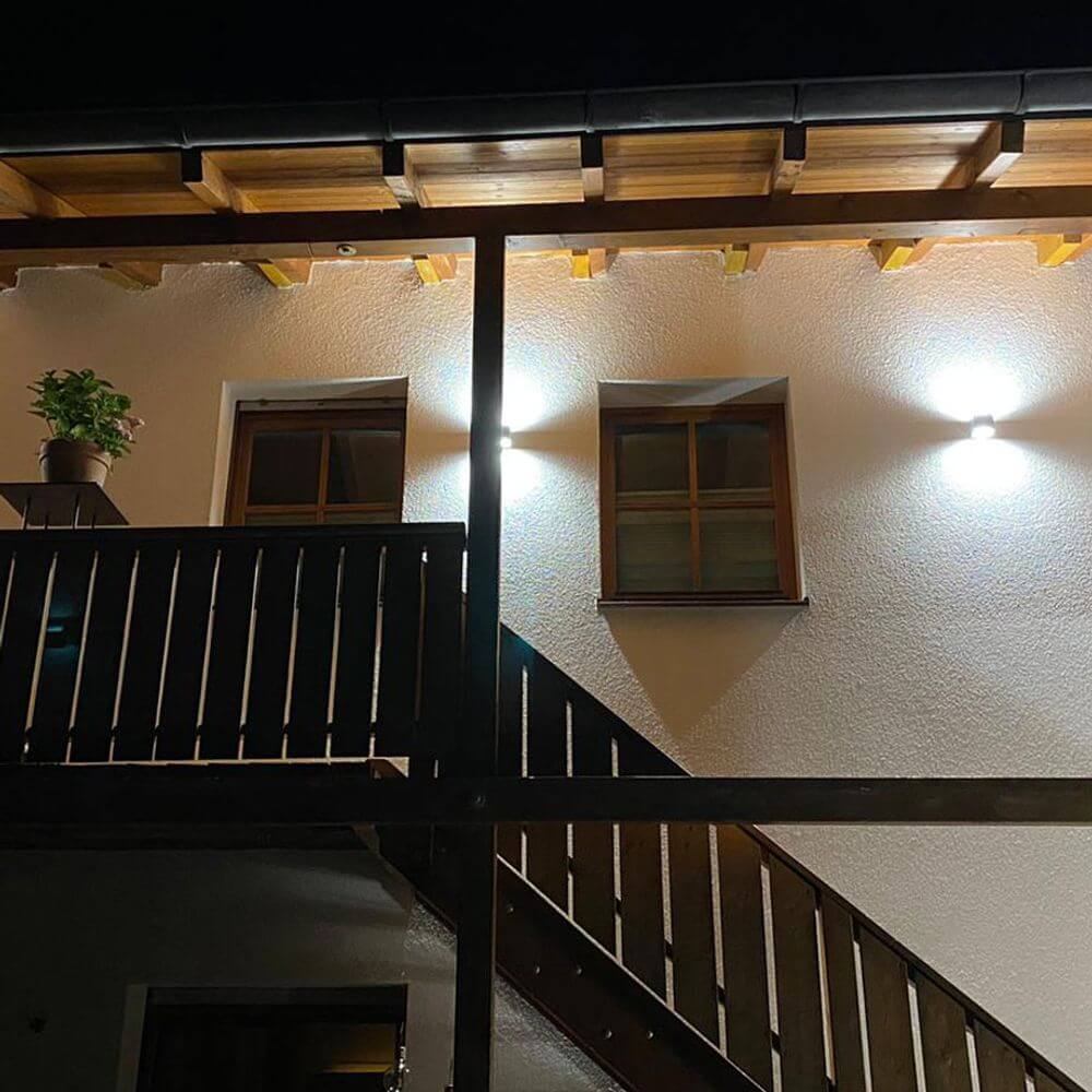 LED Außen-Wandlampe Gemini IP44 Anthrazit beleuchtet die Fassade und Fenster in der Nacht.