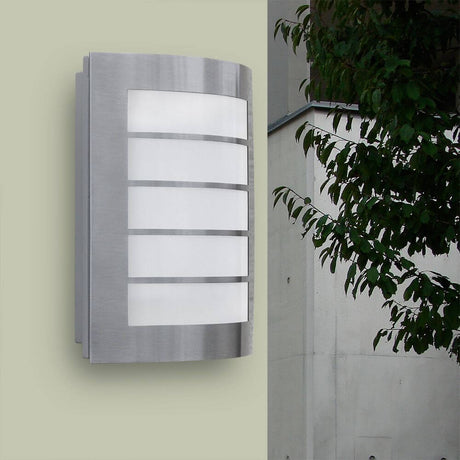 LED Applique murale extérieure Slim IP44 en acier inoxydable sur un mur avec des plantes vertes en arrière-plan.