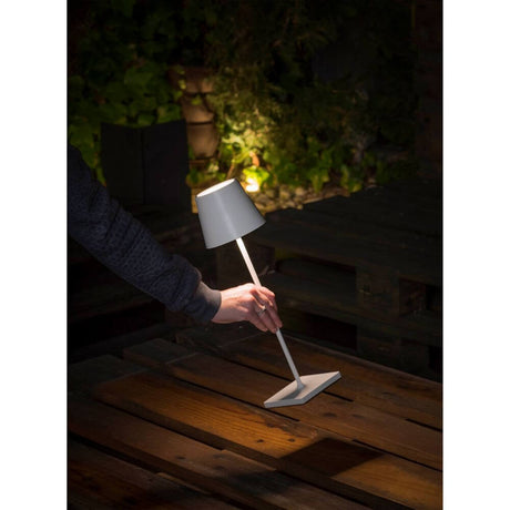 LED Akku-Außentischlampe TOC IP54 Weiß auf einem Holztisch im Freien bei Nacht.