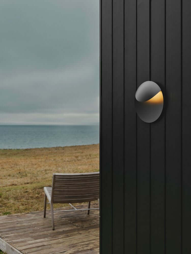 LED Außenwandlampe Valopin IP54 an einer Außenwand mit sichtbarem Meer im Hintergrund.