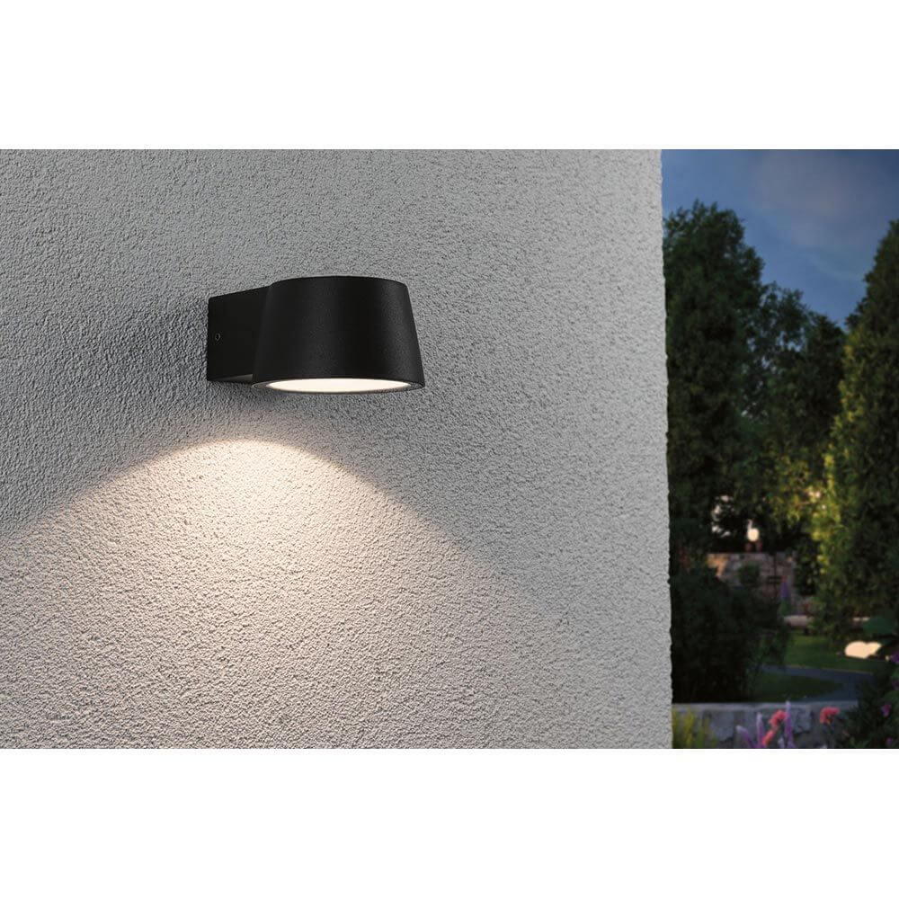 LED Außen Wandleuchte Capea Anthrazit IP44 an einer Wand, strahlt warmes Licht im Außenbereich aus.