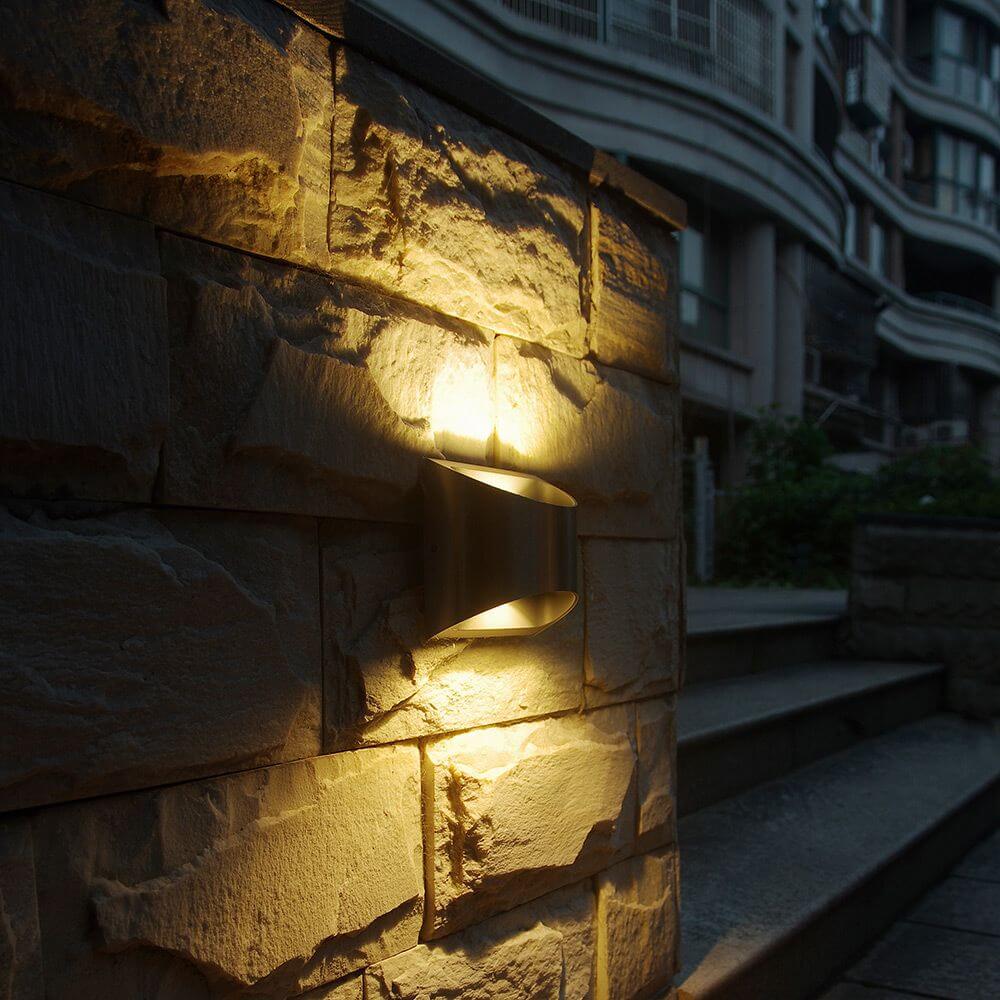 LED Außenwandleuchte Dodd IP54 Edelstahl an Steinwand mit warmweißem Licht.