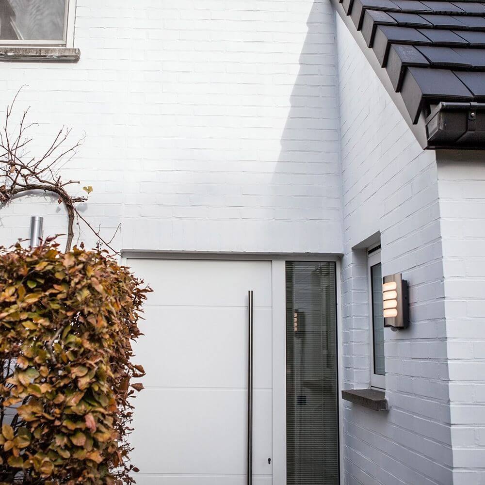LED Außenwandleuchte Farell mit Sensor IP44 Edelstahl an einer modernen Hauswand installiert.