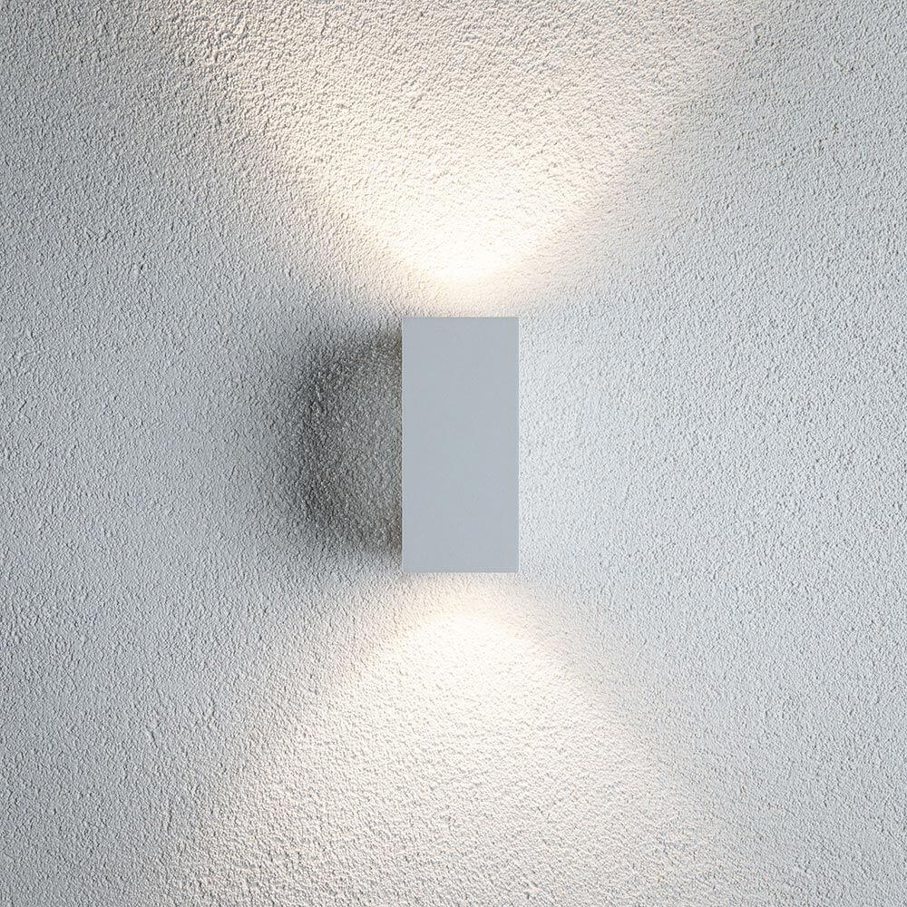 LED Außen Wandleuchte Flame Metall Weiß an einer Wand mit warmem Lichtschein.