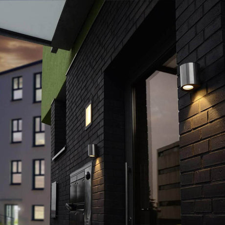 LED Outdoor wall light Ilumi IP54 chrome on a modern building at dusk.