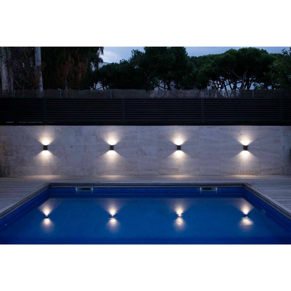 LED Außenwandleuchte LING 6W 4000K IP54 Dunkelgrau beleuchtet den Poolbereich am Abend.