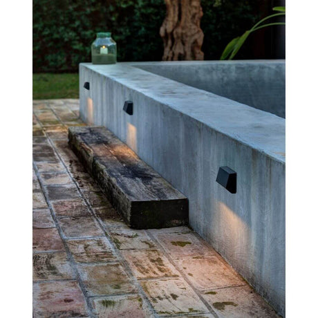 LED Surface-mounted light MUST 3000K IP65 Dark grey saltwater-resistant on a terrace with stone flooring.