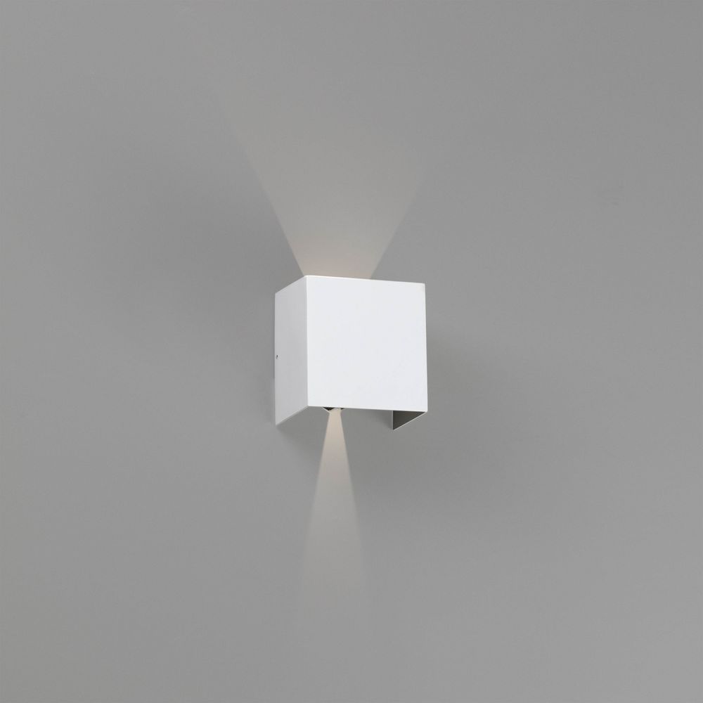 LED Außenwandleuchte OLAN 3000K IP54 Weiß an grauer Wand, moderne Beleuchtung für Außenbereiche.