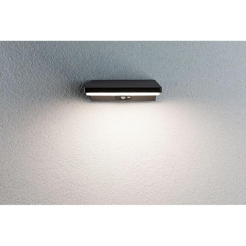 LED Außenwandleuchte Ronea mit Bewegungsmelder IP44 an Wand montiert, strahlt warmweißes Licht aus.
