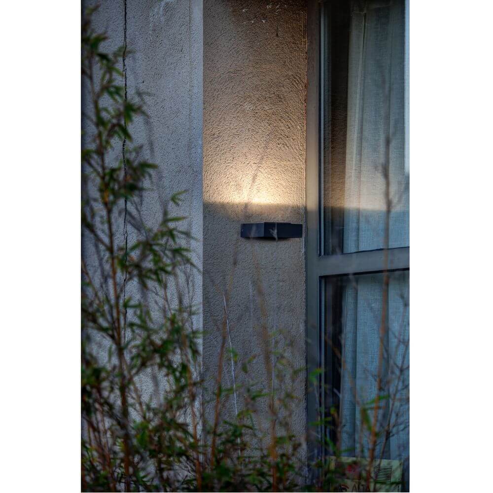 LED Außenwandleuchte TAIMA 3000K IP54 Dunkelgrau an Wand mit sanfter Beleuchtung.