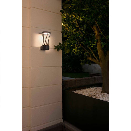 LED Außenwandleuchte TWIST 3000K IP65 Dunkelgrau an der Wand mit Pflanzen im Hintergrund