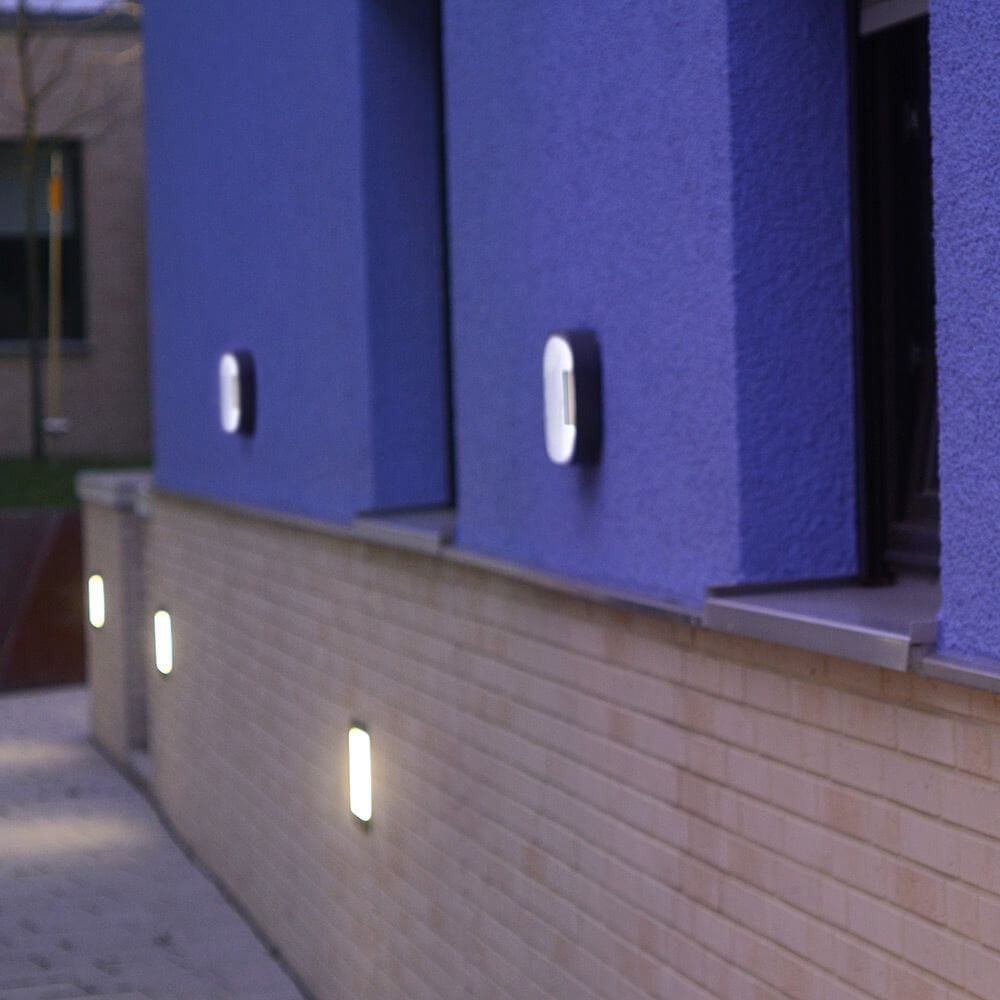 LED Außenwandleuchte Ublo 33x23cm IP44 Grau an einer Wand, modernes Design mit grauer Basis und weißem Diffusor.