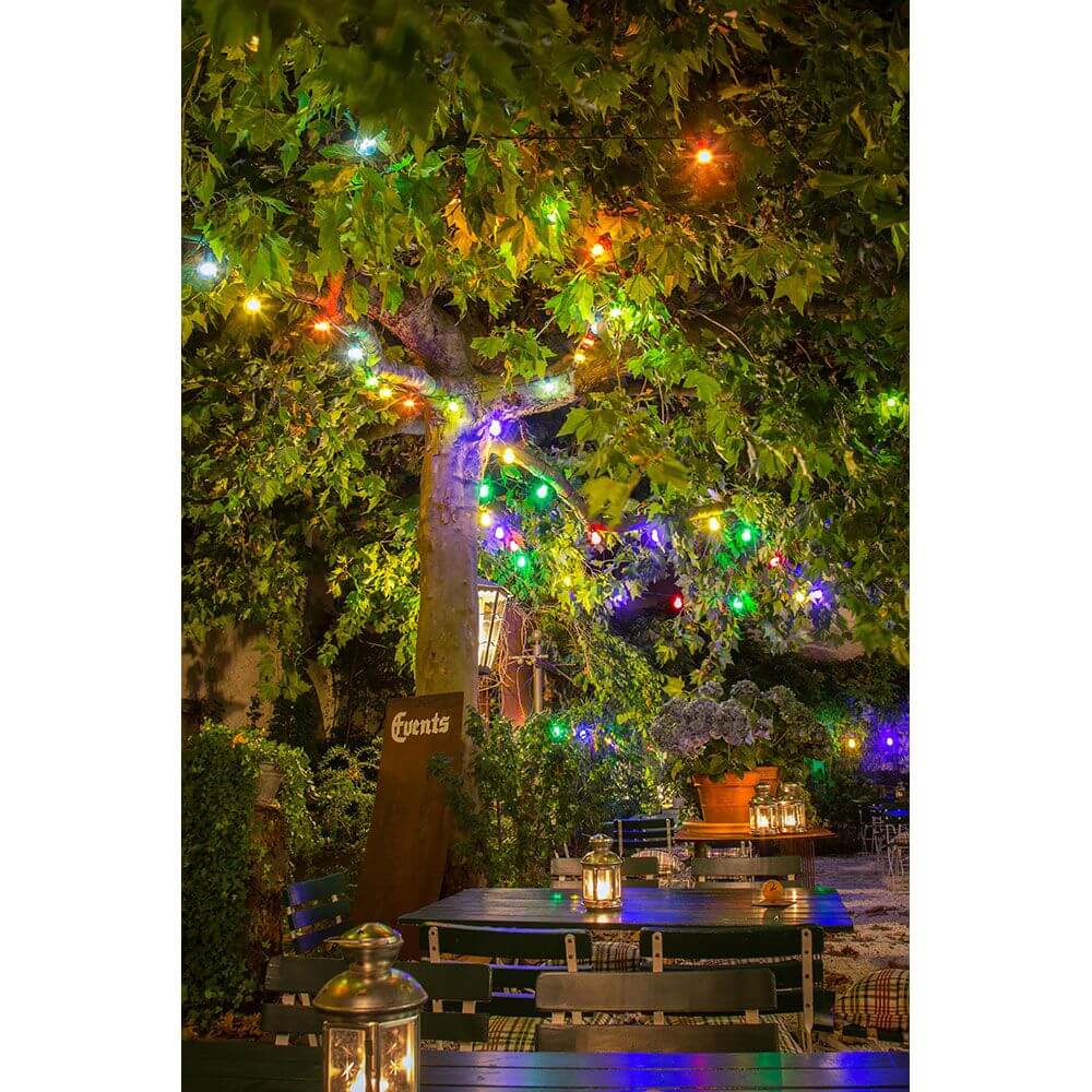 LED Biergartenkette 20er bunt milchig 160 Warmweiße Dioden 24V dekoriert einen Baum im Garten bei Nacht.