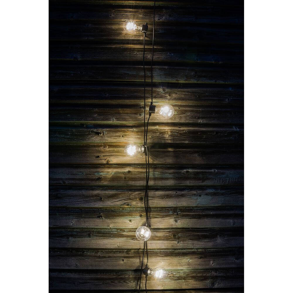 LED Biergartenkette 5er klar 40 Warmweiße Dioden Batteriebetrieb an einer Holzwand leuchtend, stimmungsvolle Beleuchtung.