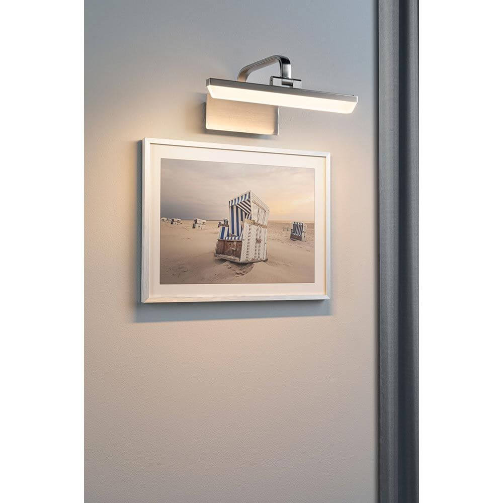 LED Spiegel- & Bilderleuchte Renan IP20 über einem Bilderrahmen an der Wand montiert, beleuchtet ein Kunstwerk.