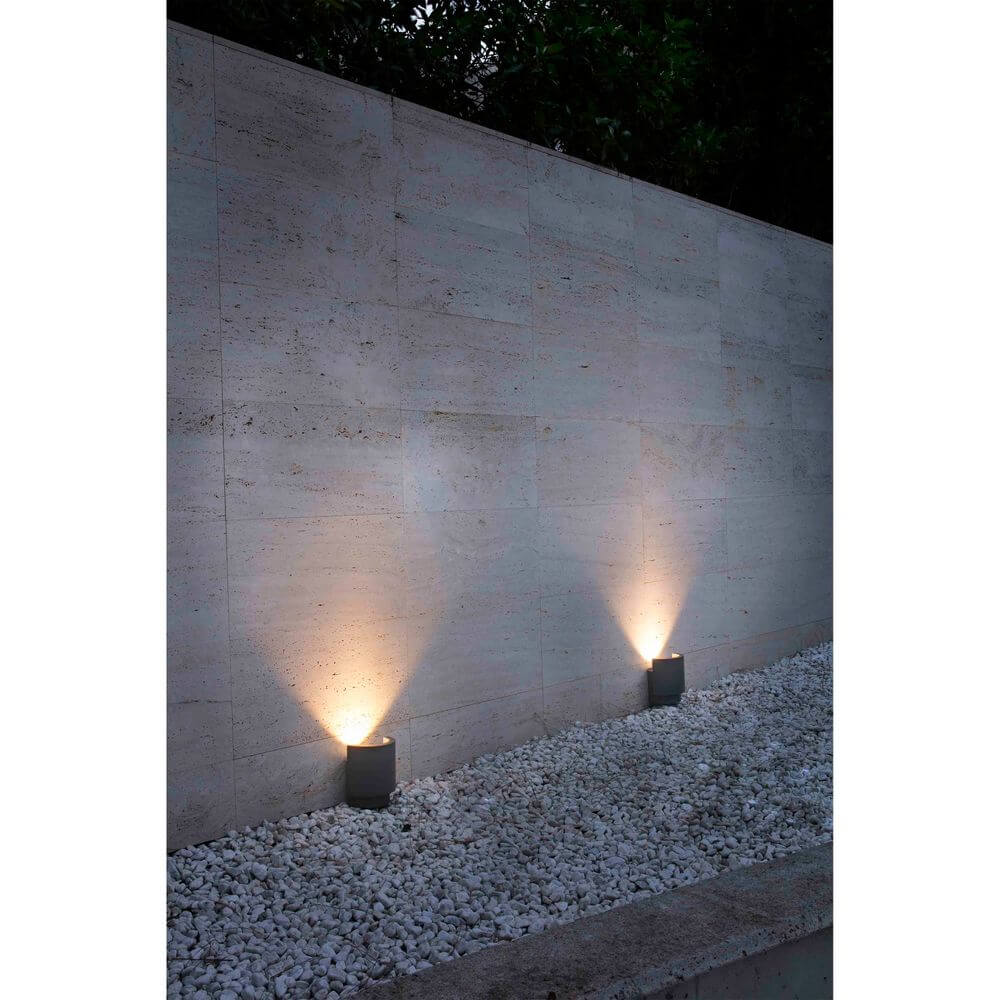 Zwei LED Boden-Aufbaustrahler NOBORU 3000K IP65 Dunkelgrau an einer Wand, die den Weg beleuchten.