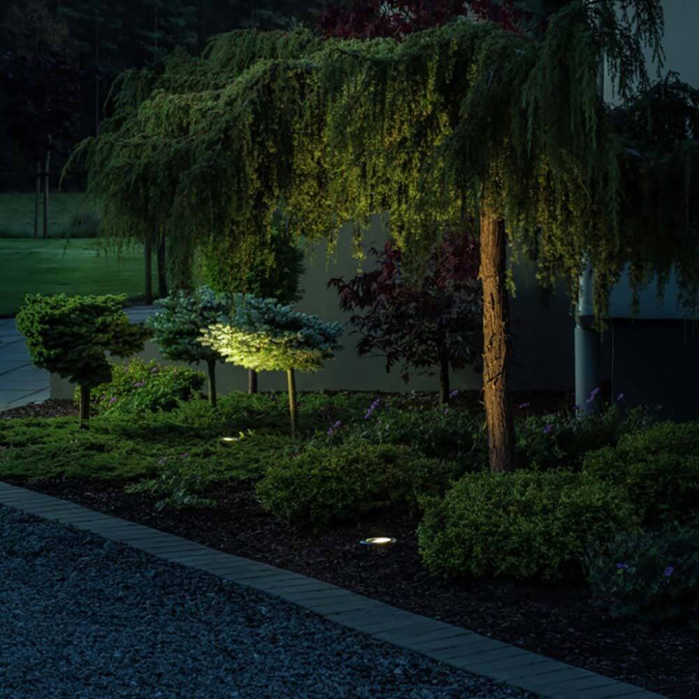 LED Boden Einbaustrahler Außen beleuchtet den Garten und die Bäume für eine stimmungsvolle Atmosphäre.