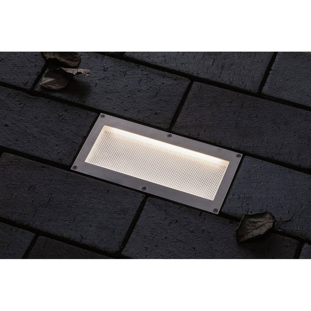 LED Bodeneinbauleuchte Brick mit Bewegungsmelder IP67 auf dunklem Untergrund mit Blättern.