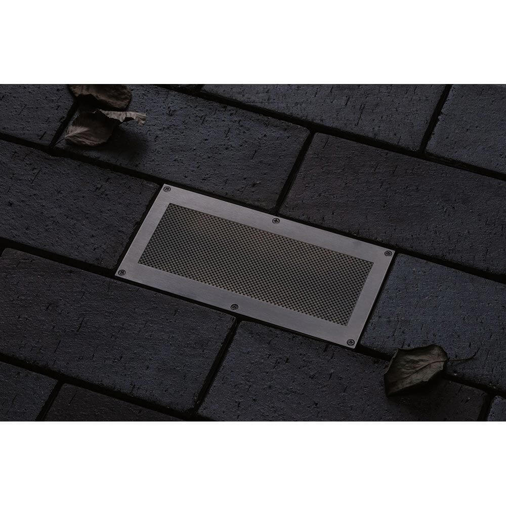 LED Bodeneinbauleuchte Brick mit Bewegungsmelder IP67 auf einem dunklen Pflastersteinboden.