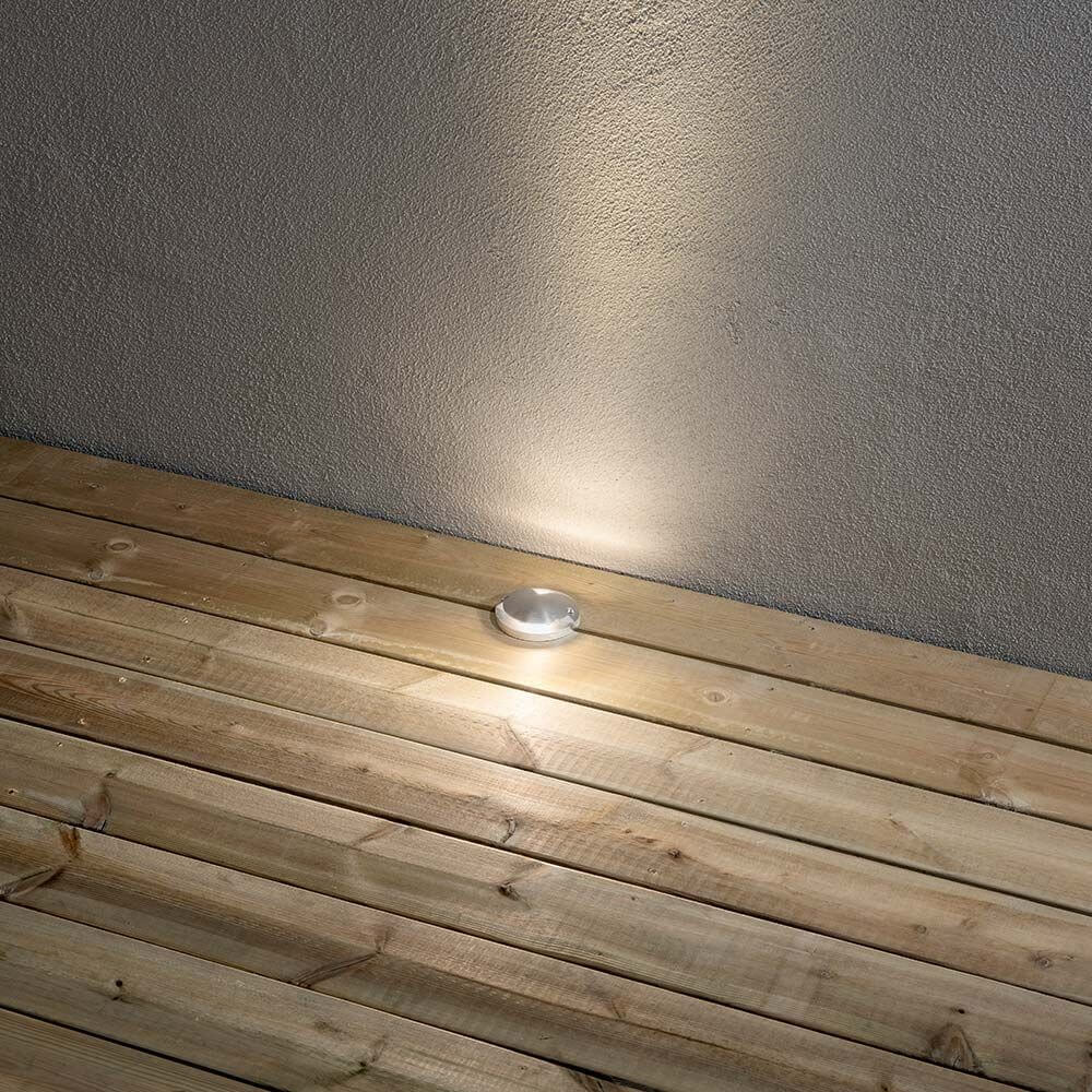LED inbyggd golvbelysning med ljusutsläpp framåt och uppåt, installerad på en träfot.