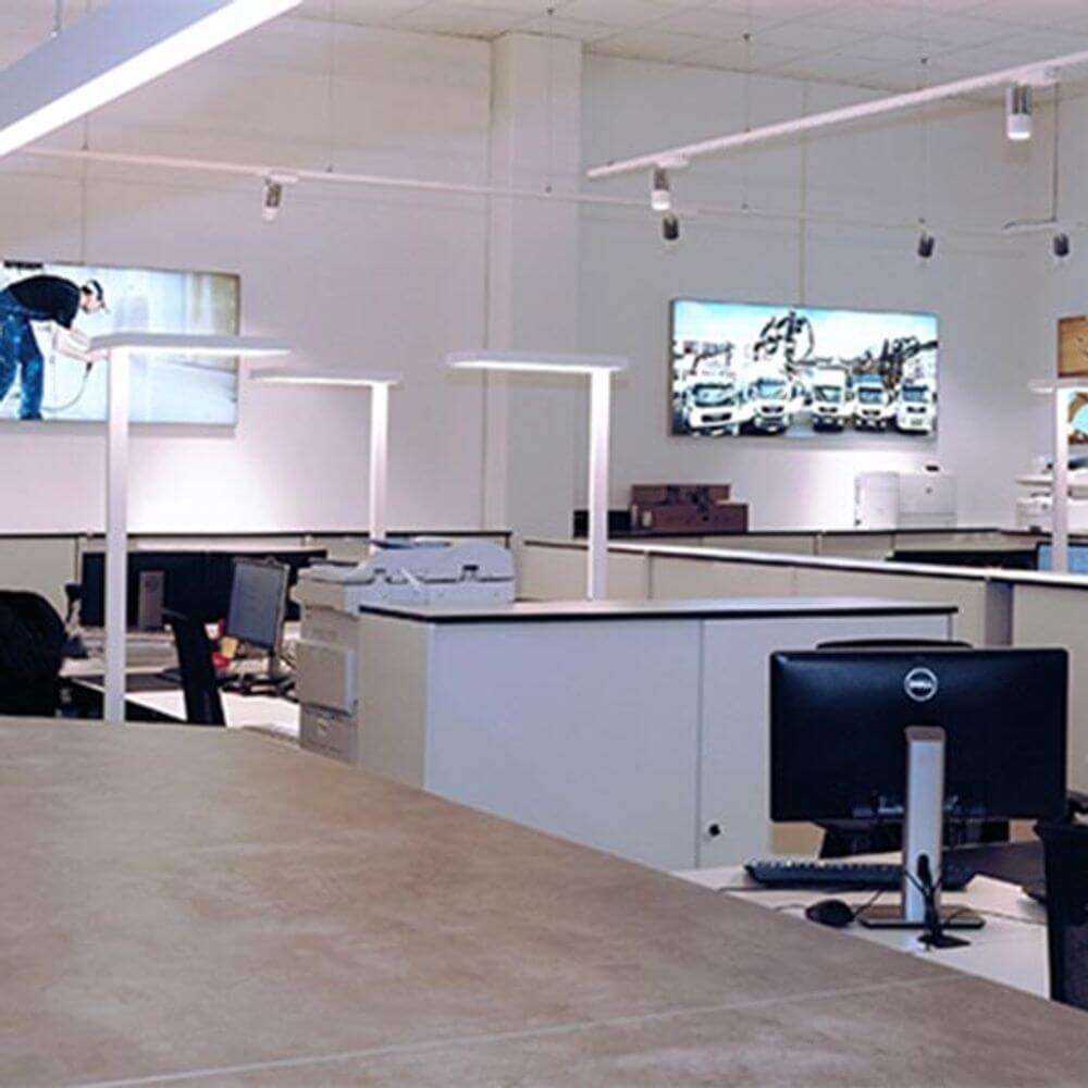 Moderne Büroeinrichtung mit LED Stehleuchten und Arbeitsplätzen in hellem, neutralem Licht.