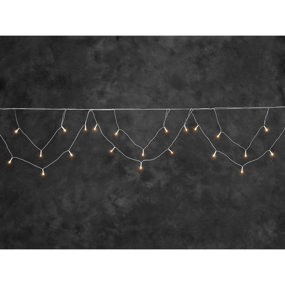 LED Dachrinnenlichterkette Bogenform 96 bernsteinfarbene Dioden IP44 auf grünem Hintergrund.